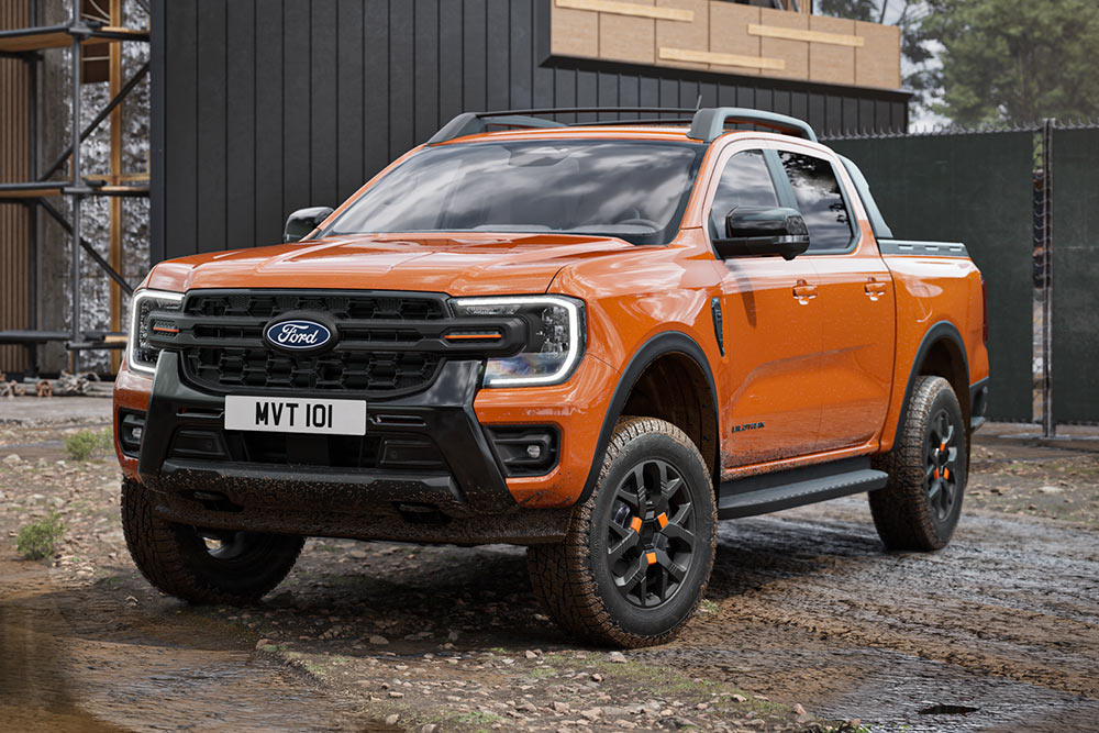 Pomarańczowy Ford Ranger zaparkowany przed budynkiem przemysłowym.