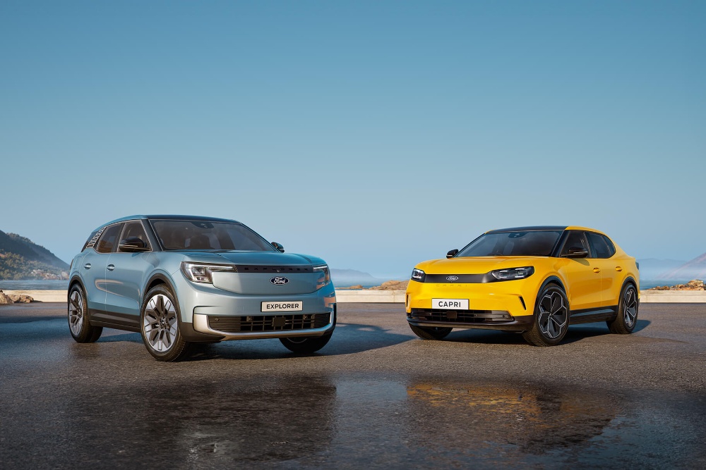 Srebrny Ford Explorer i żółty Ford Capri stoją obok siebie na mokrym asfalcie nad morzem.