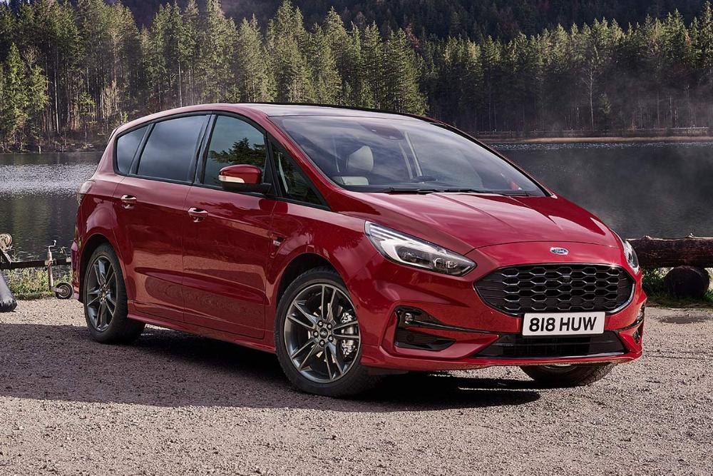 Czerwony Ford S-Max ST-Line stoi nad jeziorem otoczonym lasem, widziany z przodu.
