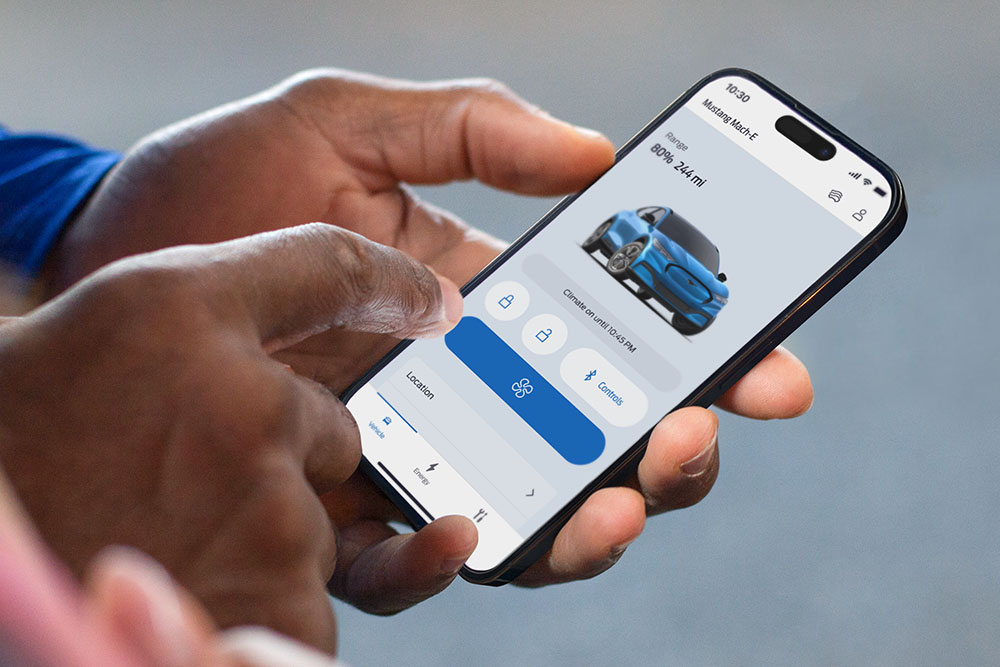 Zbliżenie na iPhone'a z uruchomioną aplikacją Ford z grafiką Forda Mustanga Mach-E i przyciskami w aplikacji.