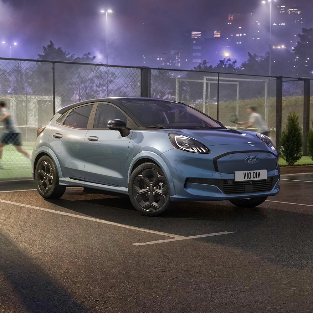 Limitowana edycja Ford Puma Gen-E w kolorze Vapour Blue z technologią BlueCruise zaparkowana obok kortu do paddla.