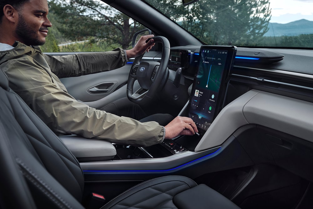 Kierowca korzystający z systemu informacyjno-rozrywkowego z ekranem dotykowym w rodzinnym SUV-ie Ford Explorer.