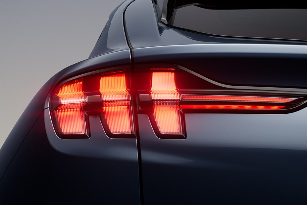 Zbliżenie na charakterystyczne potrójne światła tylne samochodu sportowego Ford Mustang Mach-E.