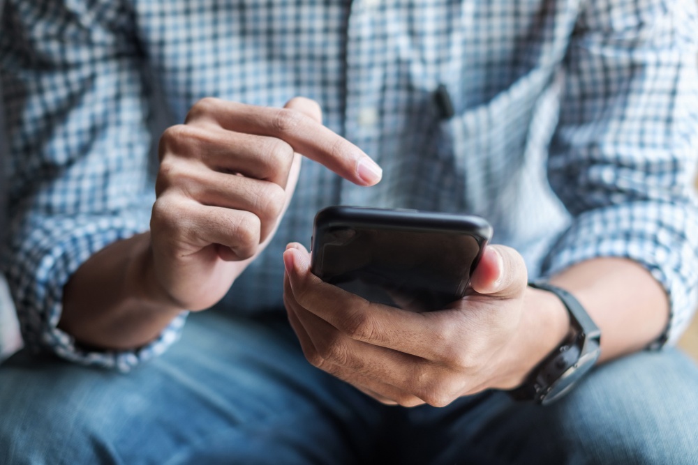 Mężczyzna w żółtej kurtce trzyma telefon