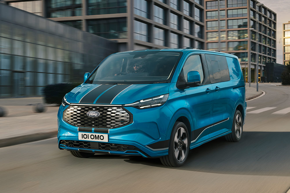 Niebieski van brygadowy Ford E-Transit Custom Sport jadący ulicą miasta.