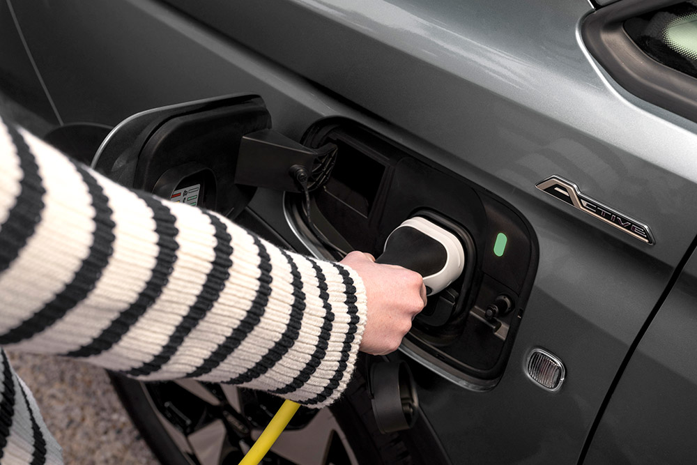 Osoba podłączająca kabel ładujący do Forda Transit Connectw wersji plug-in hybrid.
