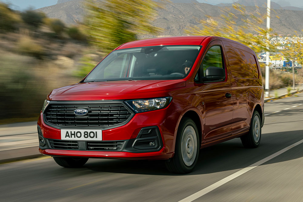 Ford Transit Connect poruszający się po drodze, z widocznym przednim grillem i automatycznymi reflektorami.
