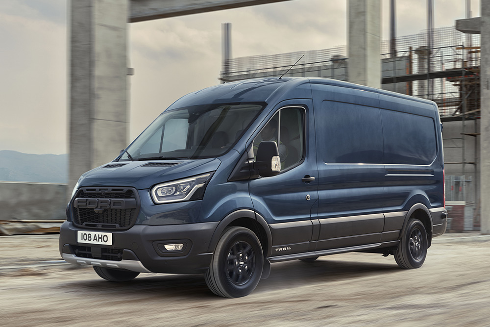 Ford Transit z opcjonalnym pakietem Trail przejeżdżający przez tereny przemysłowe.