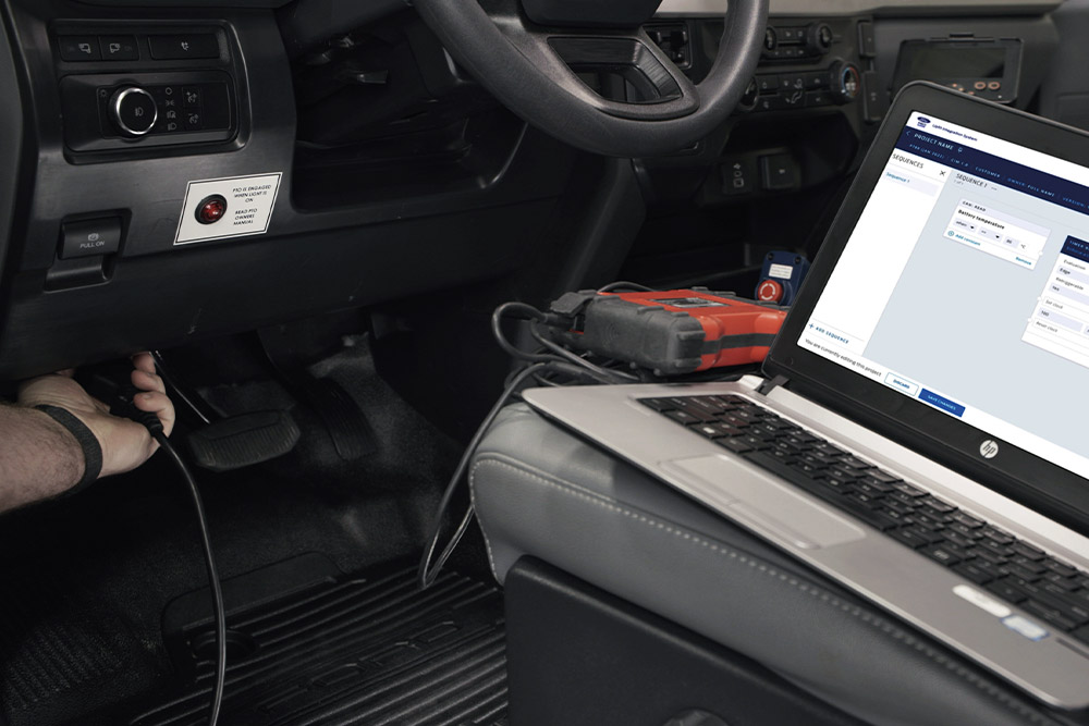  Zbliżenie na laptop podłączony do deski rozdzielczej pojazdu Forda.