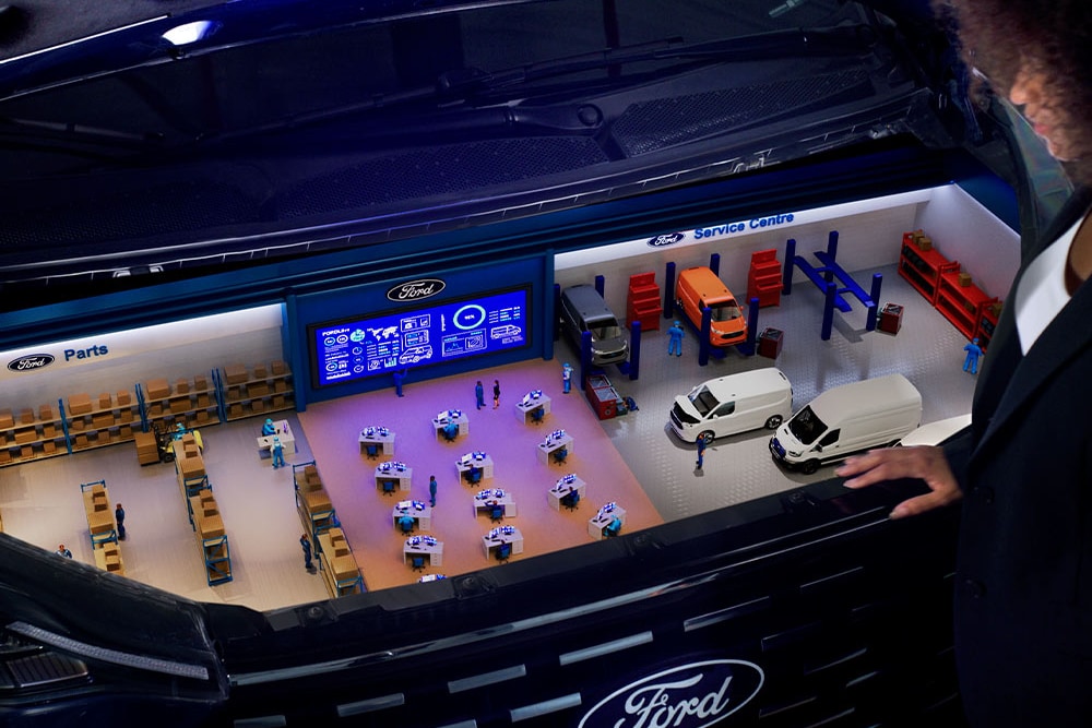 Miniaturowy model centrum serwisowego Forda w bagażniku samochodu.
